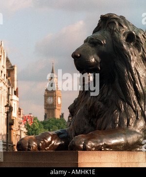 Löwenstatue am Fuß oder Sockel von Nelsons Säule in Trafalgar Square London Houses of Parliament und Big Ben im Hintergrund Stockfoto