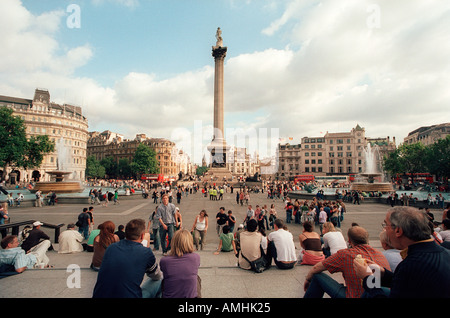 Menschen entspannen um Nelsons Säule in Trafalgar Square London Häuser des Parlaments Big Ben im Hintergrund Stockfoto