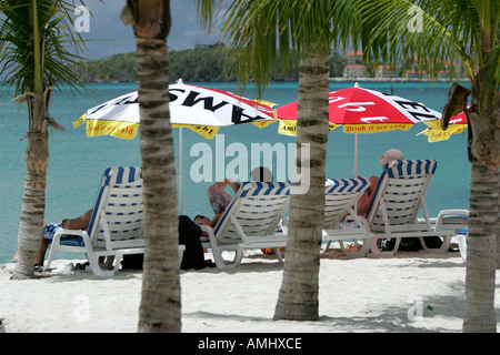 Besucher liegen im Schatten unter bunten Bier Sonnenschirme am großen Bucht Philipsburg St. Maarten Stockfoto