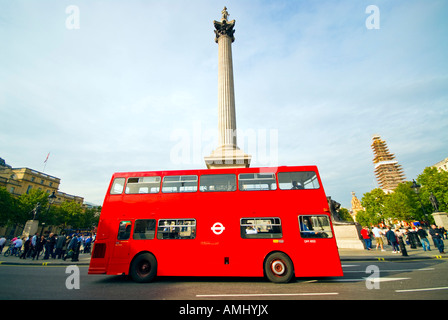 Einer von Londons berühmten roten Doppeldeckerbusse führt vor Nelson Säule am Trafalgar Square im Zentrum von London. Stockfoto