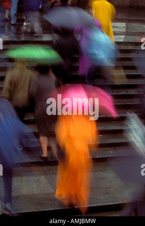Regenschirme und Publikum in Dusche verwischen Straßenszene Stockfoto