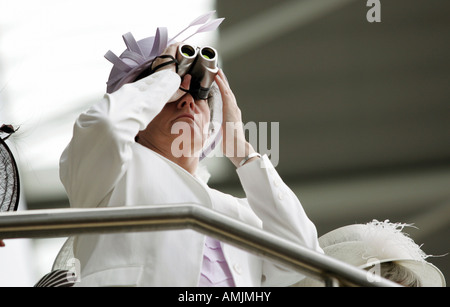 Frau, die durch ein Fernglas bei Royal Ascot Pferderennen, York, Großbritannien Stockfoto