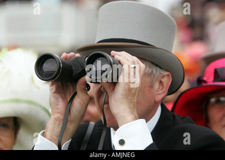 Mann auf der Suche durch ein Fernglas bei Royal Ascot Pferderennen, York, Großbritannien Stockfoto