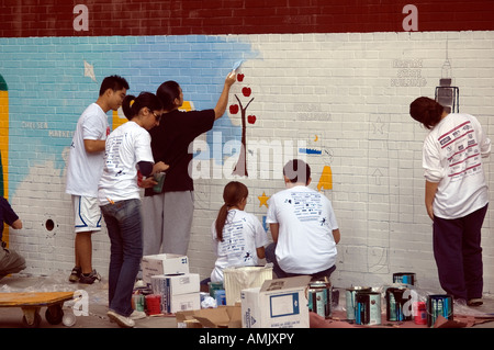 Freiwillige mit New York kümmert sich malen eine Wandbild auf der Seite der PS 33 Chelsea School in New York City Stockfoto