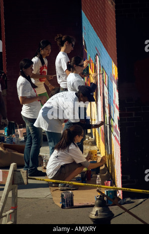 Freiwillige mit New York kümmert sich malen eine Wandbild auf der Seite der PS 33 Chelsea School in New York City Stockfoto