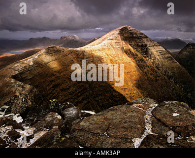 Transiente Licht bricht durch schweren grauen Wolken und malt den Gipfel des Beinn Alligin mit Licht an einem herbstlichen Nachmittag Stockfoto