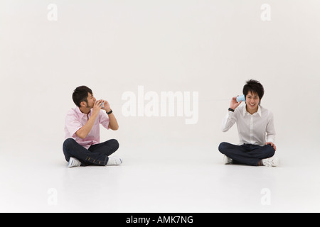 Zwei junge Männer mit String-Telefon Stockfoto