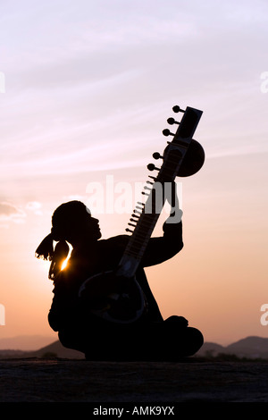 Indischen Mann spielt eine Sitar auf Felsen bei Sonnenuntergang. Indien Stockfoto