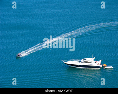 Ansicht eines waterskier durch eine Rippe (Rigid Inflatable Boat) vorbei an einem Verankerten motor yacht an einem sonnigen Sommer in Start Bay, South Devon, UK abgeschleppt Stockfoto