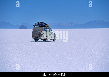 Ein Fahrzeug fährt über die verkrusteten Salz der Salar de Uyuni, der größte Salz Wohnung in der Welt. Stockfoto