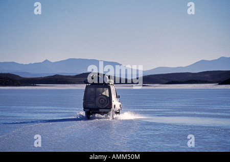 Ein Tourist fährt durch Oberflächenwasser liegen oben auf die Salzkruste auf den Salar de Coipasa Stockfoto