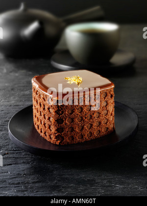 Eine handgemachte Patisserie Spezialität reichen verwöhnenden Schokoladenkuchen mit Kaffee in einem schwarzen Tisch Einstellung gefüllt Stockfoto