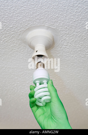 Grüne Hand, die Umstellung auf eine Energie effiziente Leuchtmittel in Decke Stockfoto