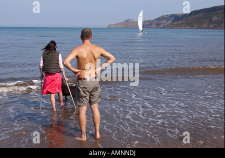 Paar Paddeln im Meer, Frauen auf Krücken. Runswick Bay North Yorkshire England. Stockfoto