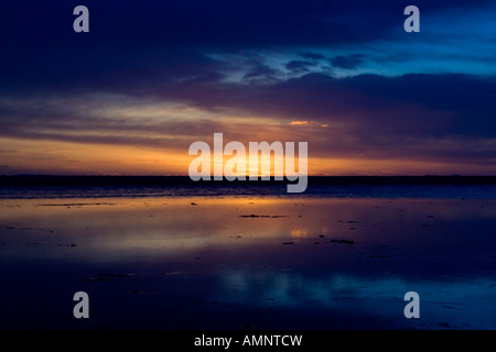 Sonnenuntergang am Strand von Tarifa. Symmetrisches Bild zeigen den Sonnenuntergang spiegelt sich im nassen Sand bei Ebbe. Stockfoto