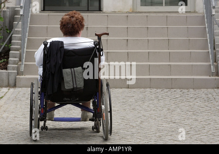 Frau in einem Rollstuhl vor Treppen Stockfoto