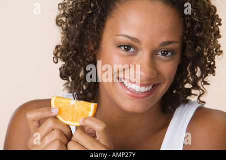 Afrikanerin Holding orange slice Stockfoto