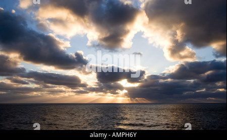 Bewölkten Sonnenuntergang mit Sonnenstrahlen, die durch Höchststand Stockfoto