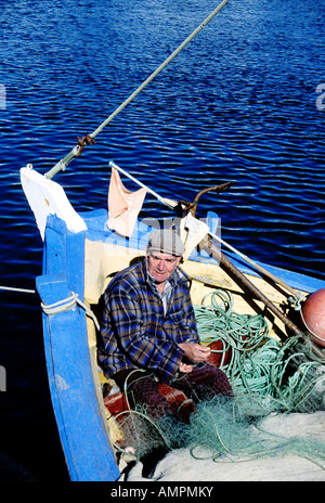 ein Fischer sein Netz in einem Boot auf dem Fluss Gilao bei Tavira Algarve Portugal ausbessern Stockfoto
