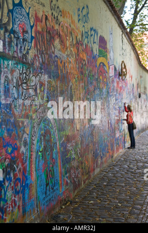 Eine junge Frau fügt einige Kunstwerke, die John-Lennon-Mauer auf Grand Priory Square in Prag-Böhmen-Tschechien. Stockfoto