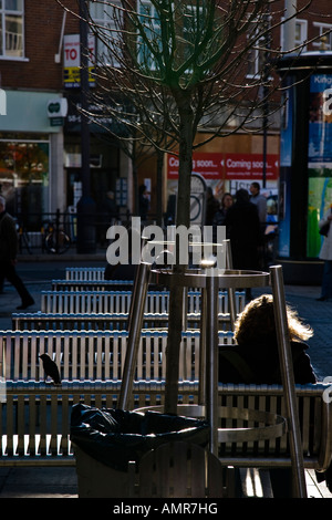 Ein Mädchen sitzt in einem Café-Tisch gegen die Morgensonne Kingston upon Thames, Surrey, England. Stockfoto