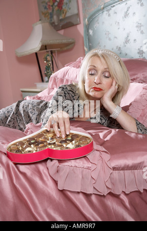 Frau im Bett Schokolade essen Stockfoto