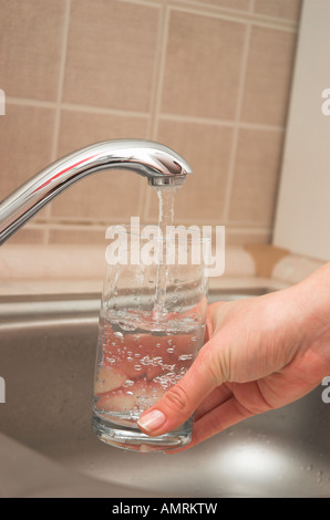 Frau Glas Wasser aus Spüle Stockfoto