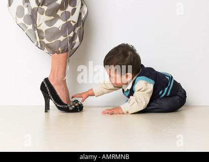 Baby Boy fasziniert von Mutters Schuhe Stockfoto