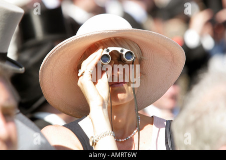 Frau, die durch ein Fernglas bei Pferderennen in Epsom, Großbritannien Stockfoto