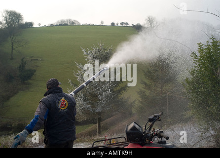 Mann, der arbeitet für Schnee Dekoschnee Unternehmen Spritzen landwirtschaftlichen Gebäudes in Vorbereitung für die Dreharbeiten zu einer Szenenverlaufs im tiefen Winter eingestellt Stockfoto