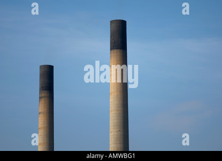 Industrielle Schornsteine vor einem blauen Himmel steigen. Stockfoto