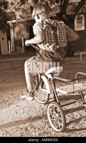 kleiner Junge im alten Stil Kleidung reitet ein Dreirad Stockfoto