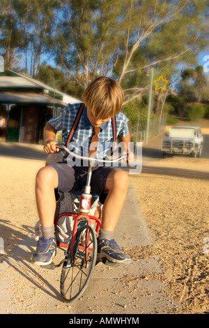 kleiner Junge im alten Stil Kleidung reitet ein Dreirad Stockfoto