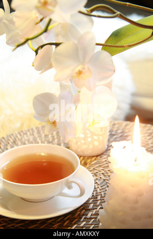 Nahaufnahme der Tasse schwarzer Tee und brennende Kerze Stockfoto