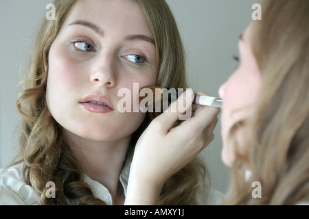 Reflexion der jungen Frau, die Anwendung von Rouge mit einem Pinsel im Spiegel Stockfoto