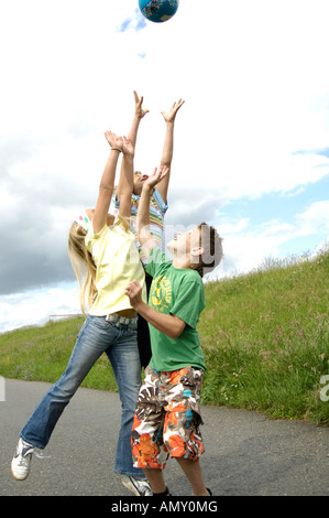 drei Kinder spielen mit Ball unterwegs Stockfoto