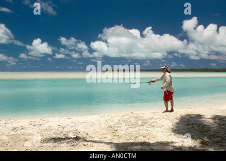 Ein Mann, der vom Strand aus im türkisfarbenen Wasser der Aitutaki Lagoon, den Cook Islands, angeln kann Stockfoto