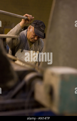 Ältere Handwerker bei der Arbeit in kleinen Werkstatt in Birmingham. Der Mann läuft eine Maschine beim Schleifen von Marmor beteiligt. Stockfoto