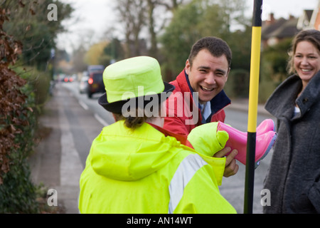 Britische "Lollipop Lady" hilft, ein Mann und eine Frau die Straße überqueren Stockfoto