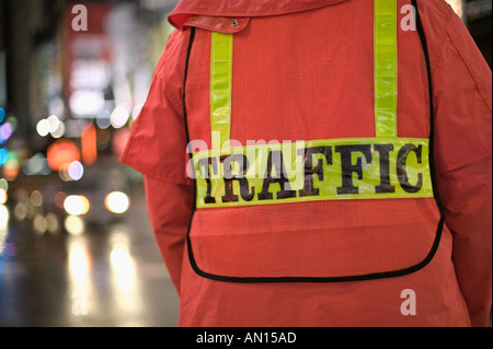 Verkehrspolizist tragen helle orange reflektierende regen Getriebe Regie Verkehr an regnerischen Nacht in New York Times Square New York Stockfoto