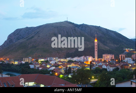 Blick über die Stadt bei Sonnenuntergang. Minarett der Moschee. Franziskaner-Kloster und Kirche. Hügel mit einem Kreuz auf dem Hügel im Hintergrund historische Stadt von Mostar. Föderation Bosne ich Hercegovine. Bosnien-Herzegowina, Europa. Stockfoto
