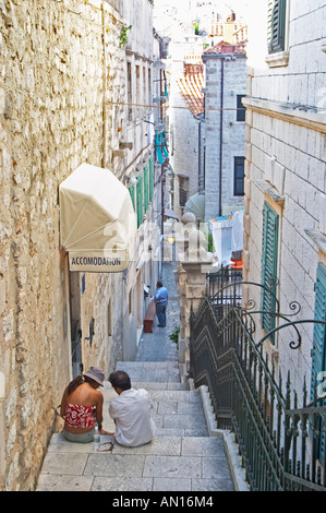 Zwei Menschen sitzen auf der Treppe eine steile schmale Straße vor einem Hotel Dubrovnik Altstadt. Dalmatien, Kroatien, Europa. Stockfoto