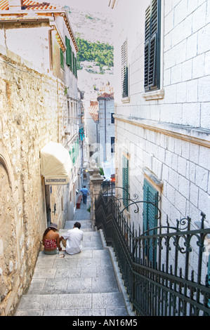 Zwei Menschen sitzen auf der Treppe eine steile schmale Straße vor einem Hotel Dubrovnik Altstadt. Dalmatien, Kroatien, Europa. Stockfoto