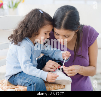 Hispanische Mutter Tochter Krawatte Schuh zu helfen Stockfoto