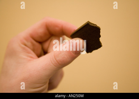 Ein kleines Stück die illegale Droge Haschisch (Cannabisharz) statt einer mans Finger Stockfoto