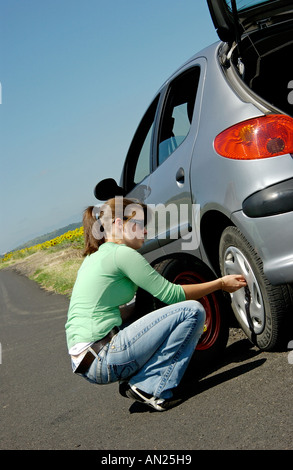 Frau der Radwechsel / Reifen für einen Ersatz Reifen auf ihrem Auto Stockfoto