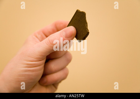 Ein kleines Stück die illegale Droge Haschisch (Cannabisharz) statt einer mans Finger Stockfoto