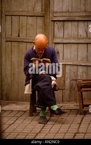 Ein Mann liest in Yangshou China. Er trägt die traditionelle Mao-Anzug. Stockfoto