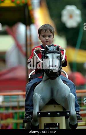 sechs Jahre alter Junge auf einem Rummelplatz-Pferd. Stockfoto
