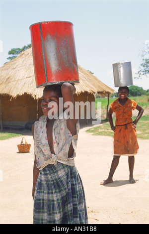 Junge Mädchen, die Portierung undichte Eimer Wasser in Simbabwe Stockfoto